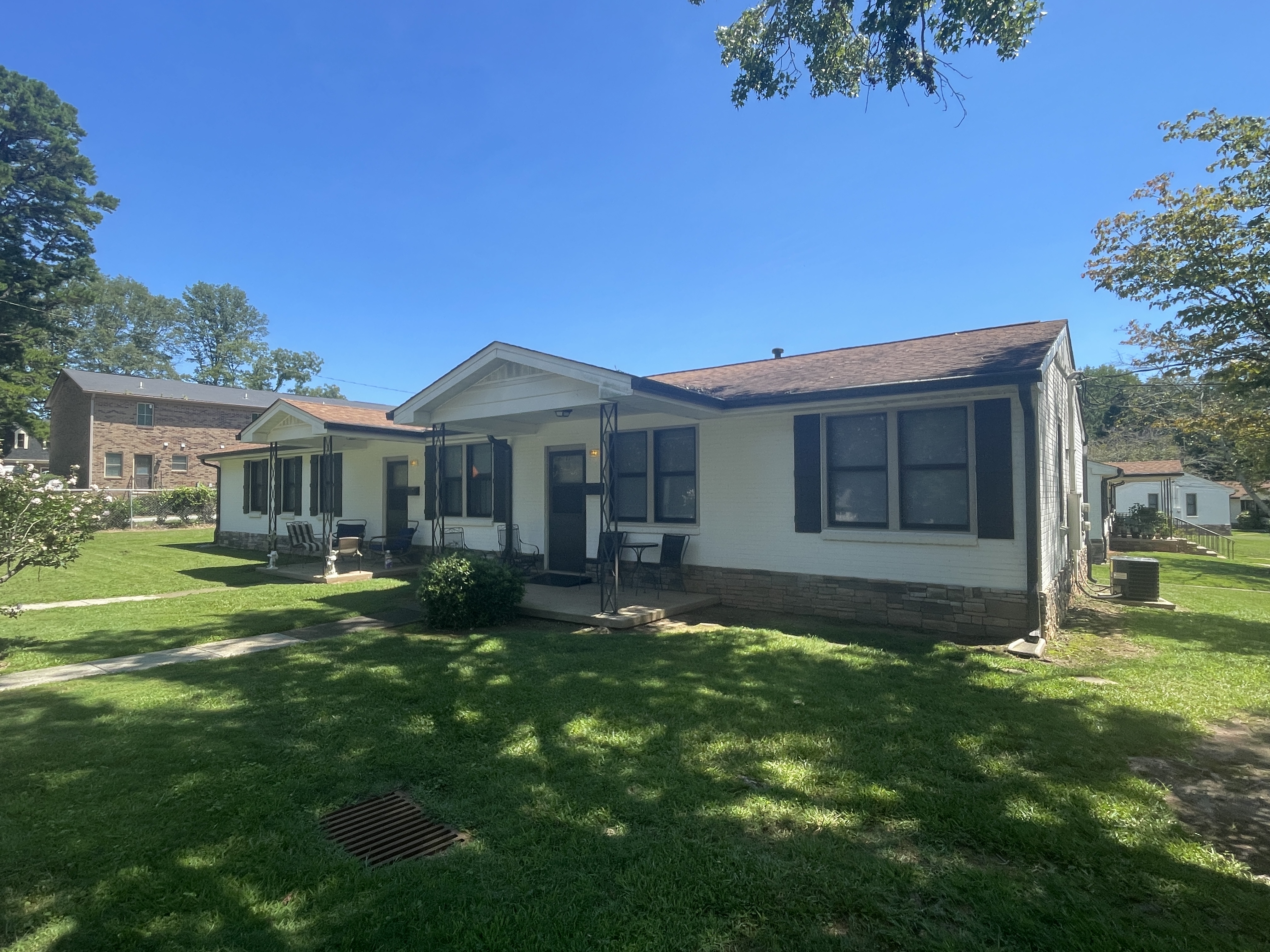 Shows the front yard and entrance to a single story, brick, duplex style rowhouse